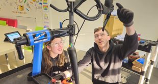 Connor offering training in his store, showing a young woman a bike in a stand