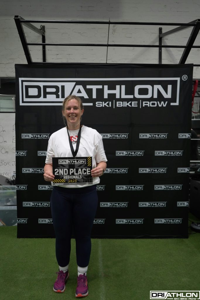 Hannah Wilson stands against a driathlon backdrop with her 2nd place award