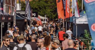 Crowd attending Sea Otter Europe with exhibitor banners and flags at either side of the walkway